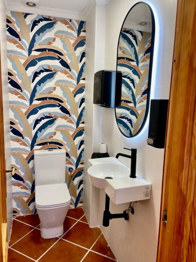 Baño pequeño con papel tapiz de hojas y lavabo moderno. Espejo circular. 